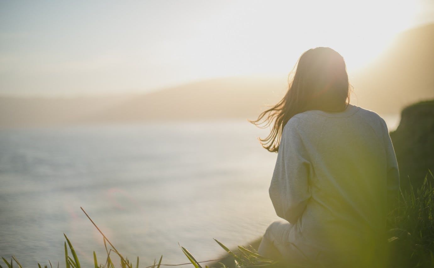 woman wearing gray long-sleeved shirt facing the sea